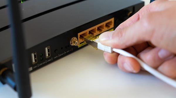 person plugging in a cord into a router